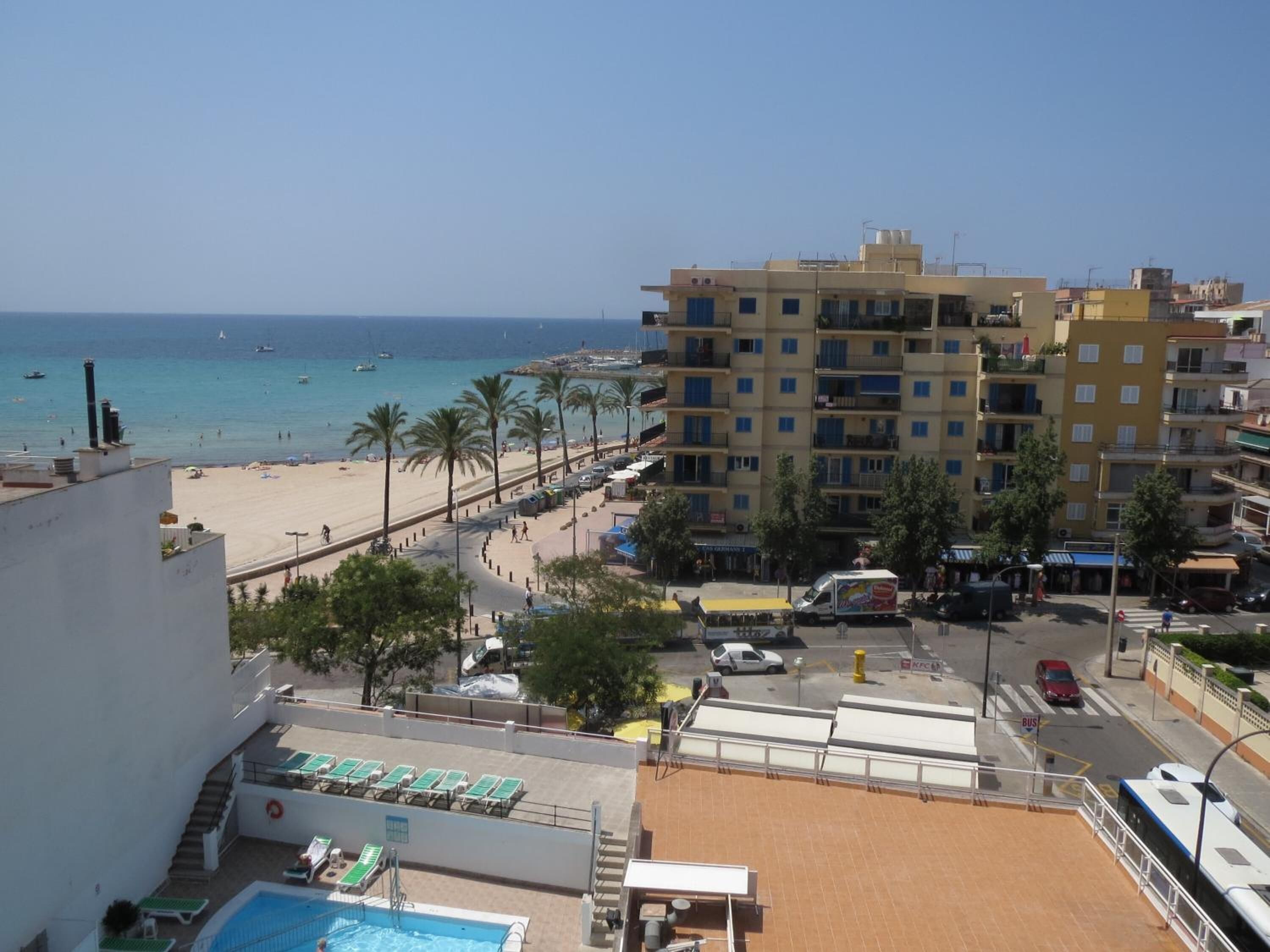 Un hotel con piscina, vista al mar y una calle con vehículos.