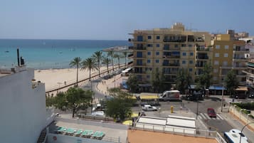 Un hotel con piscina, vista al mar y una calle con vehículos.