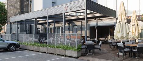 A modern outdoor seating area with a covered patio, outdoor tables, and umbrellas.