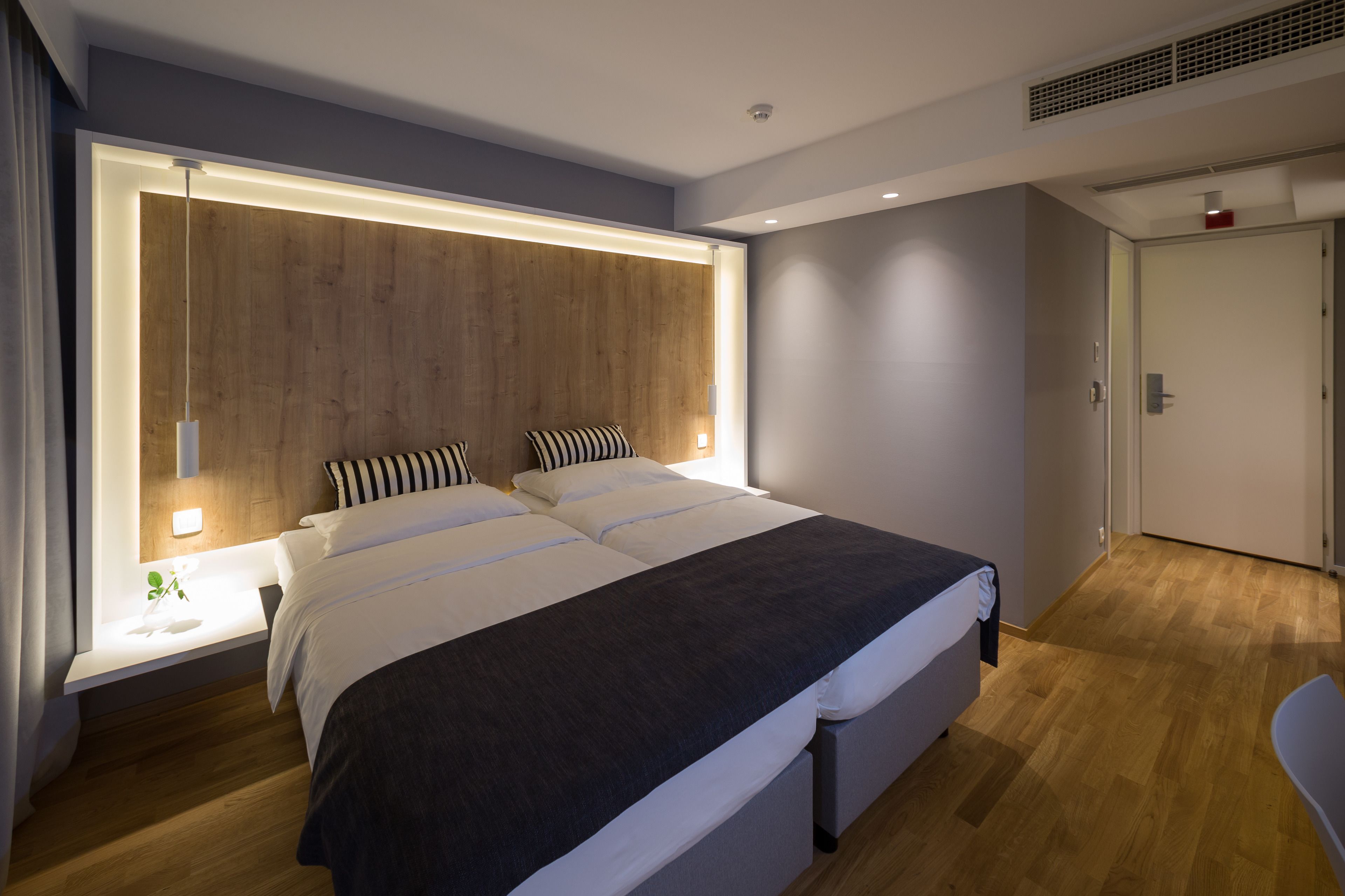 Un dormitorio moderno con una cama grande, mesitas de noche y un cabecero de madera.