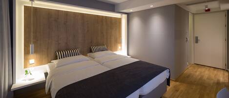 Un dormitorio moderno con una cama grande, mesitas de noche y un cabecero de madera.