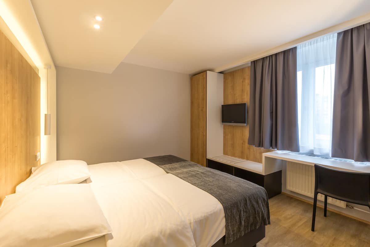 A modern hotel room with a large bed, a desk, and a TV.
