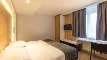 Una habitación de hotel moderna con una cama grande, un escritorio y un televisor.