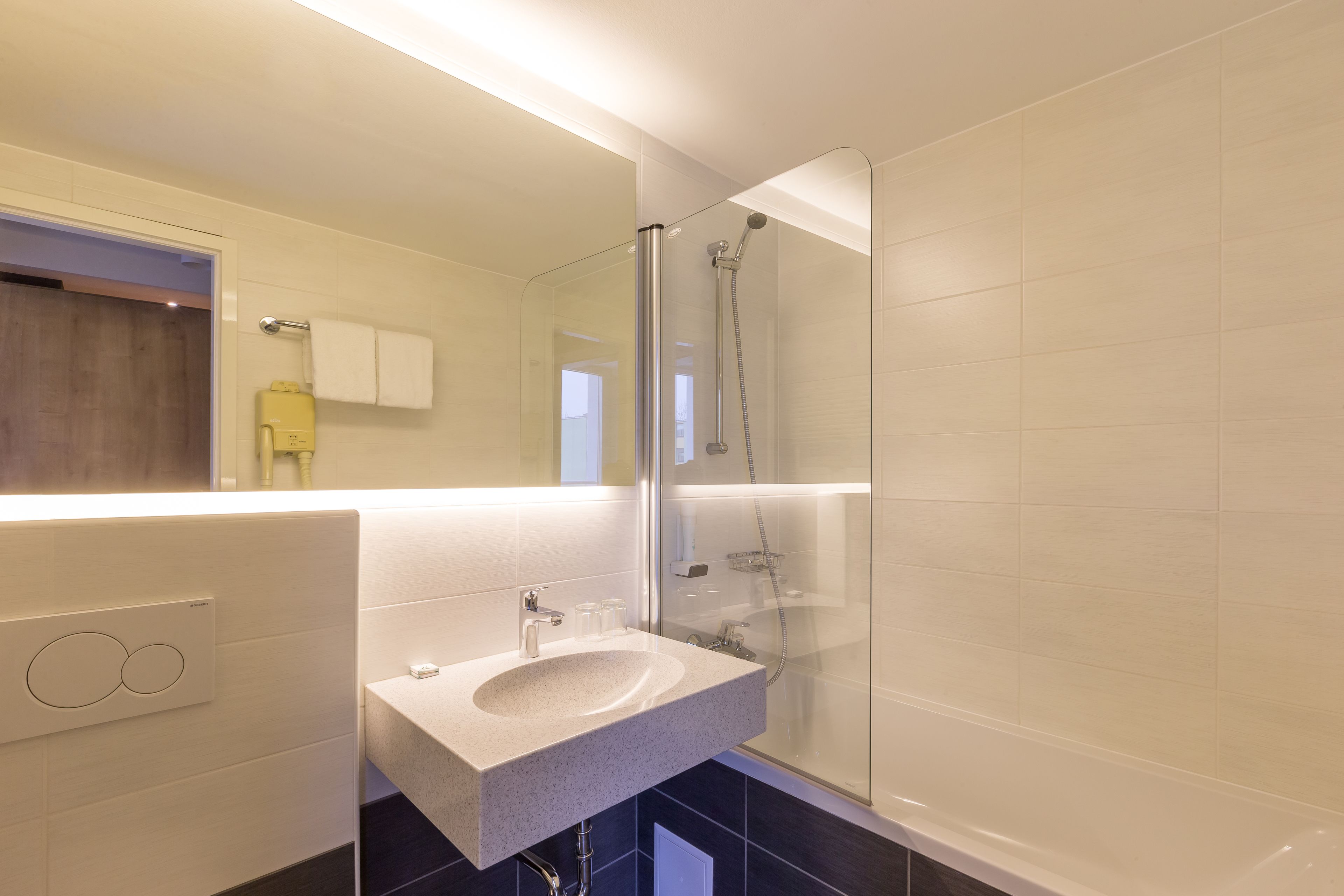 A modern bathroom with a glass-enclosed shower, a built-in sink, and a mirror above the sink.