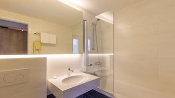 A modern bathroom with a glass-enclosed shower, a built-in sink, and a mirror above the sink.
