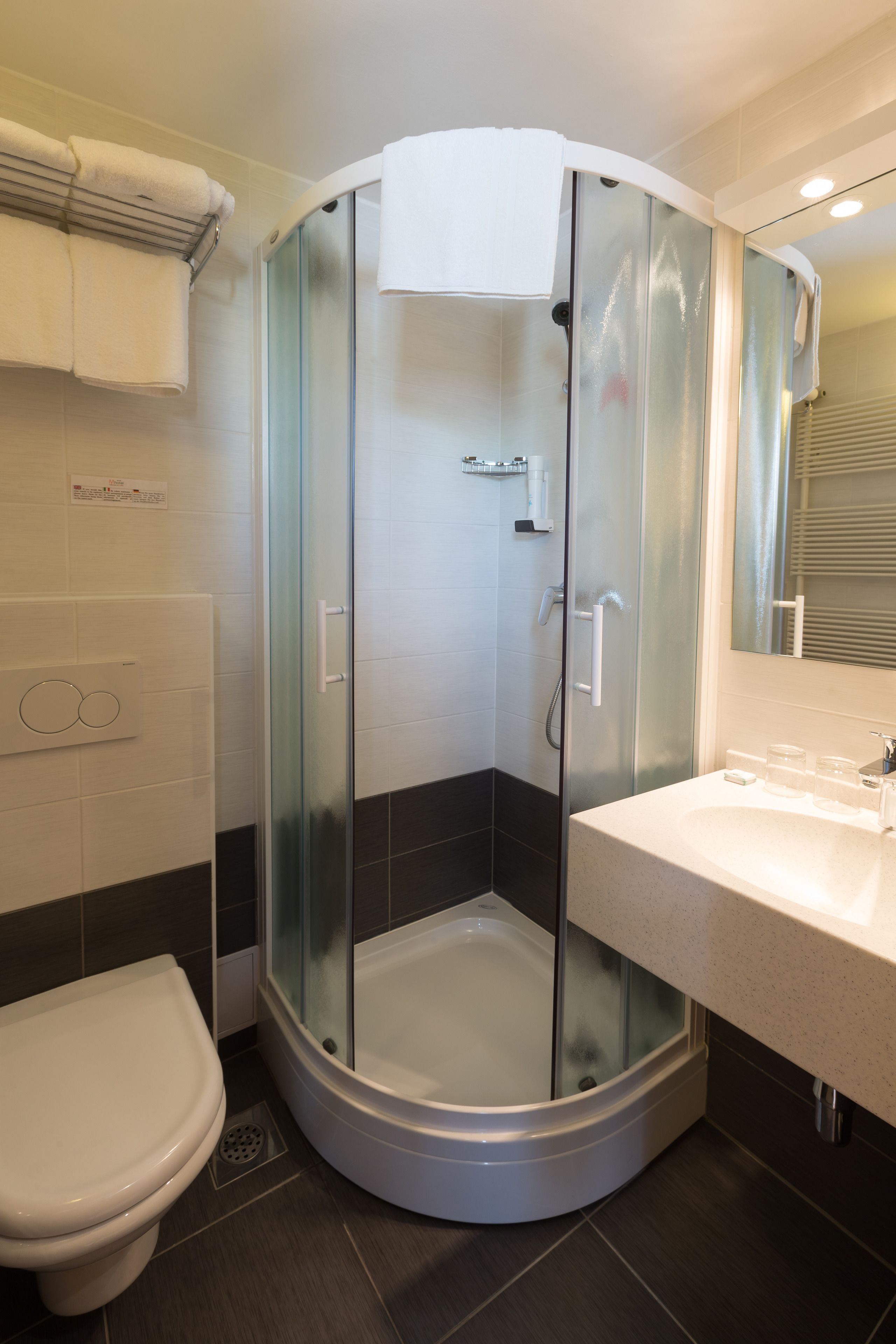 Un baño moderno con ducha de vidrio, lavamanos blanco y retrete.
