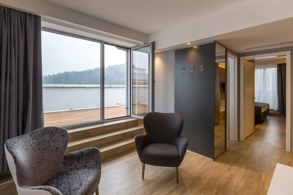 A modern room with a large window, a dark armchair, and a wooden floor.