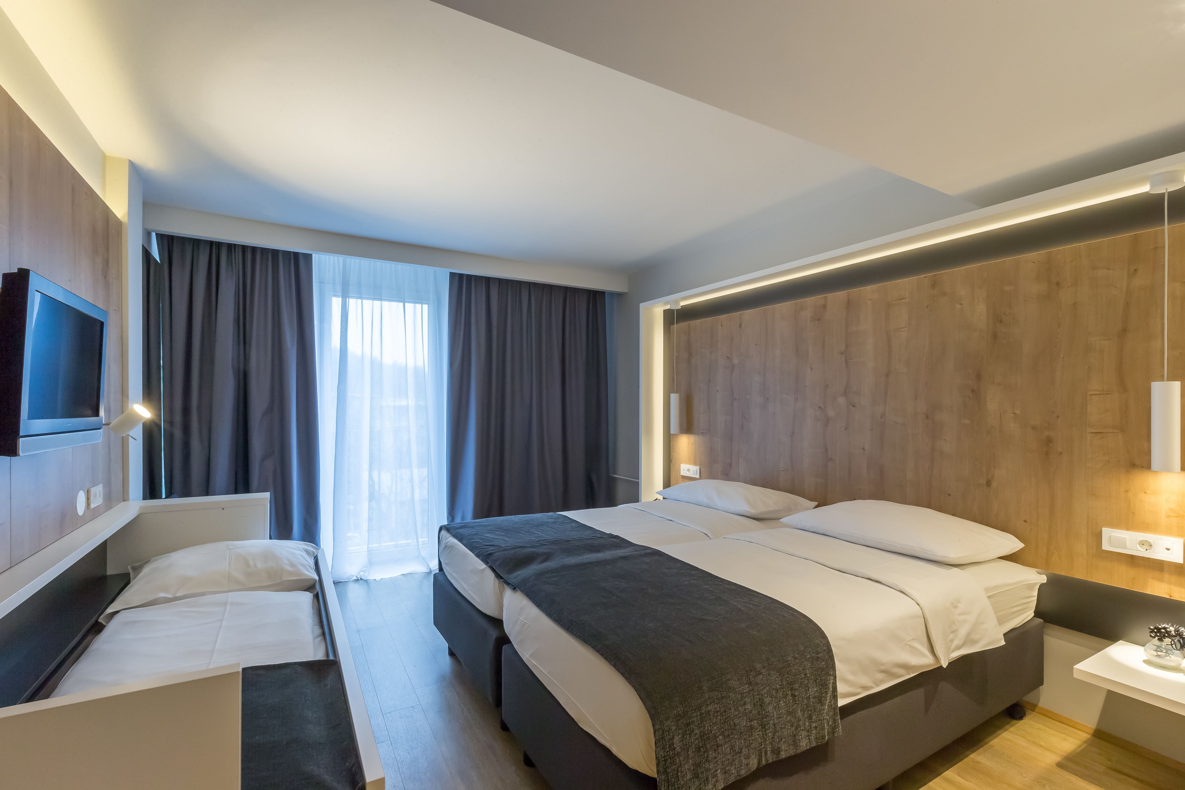 A modern hotel room with a large bed, a desk, and a TV.
