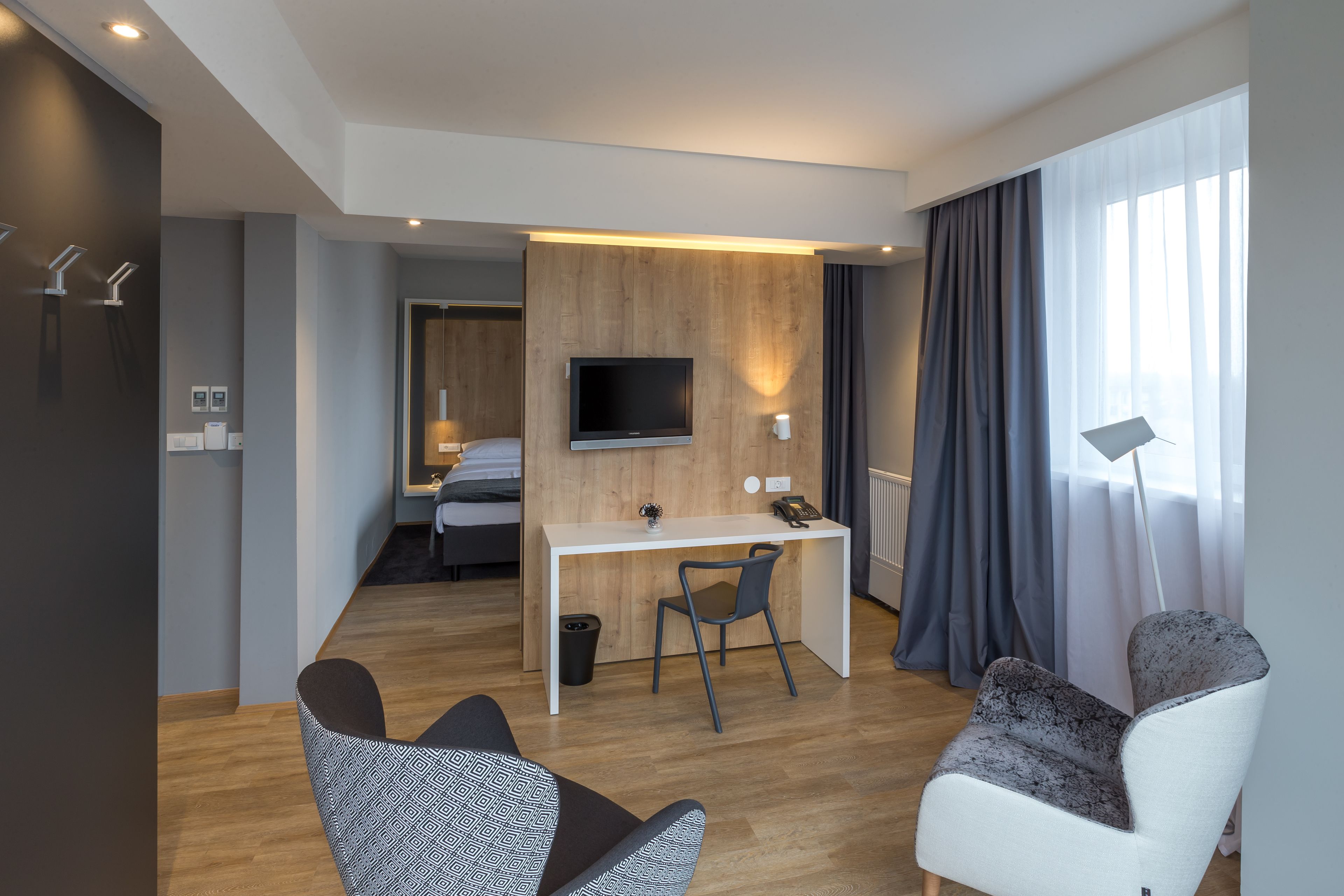 Een moderne hotelkamer met een houten bureau, een televisie, een stoel en een bank.