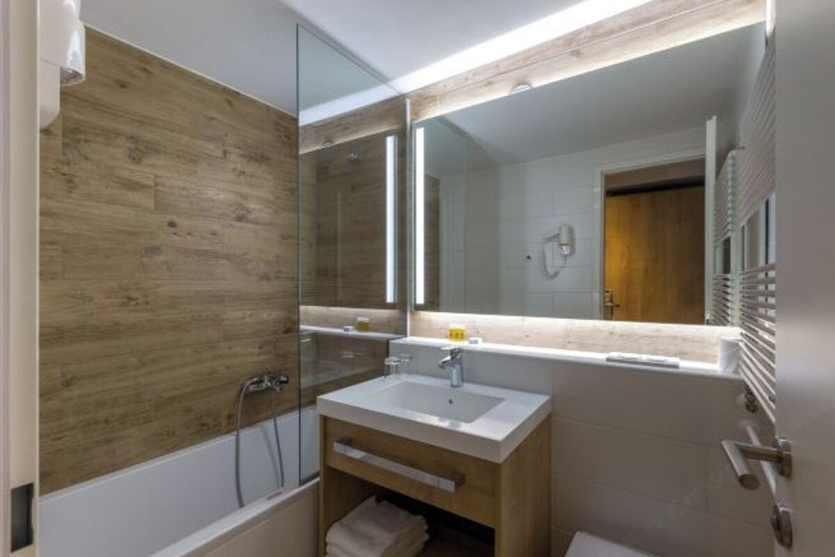 A modern bathroom with a wooden vanity, a large mirror, and a shower enclosure.