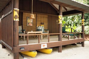 A wooden structure with a porch, seating area, and a small table.