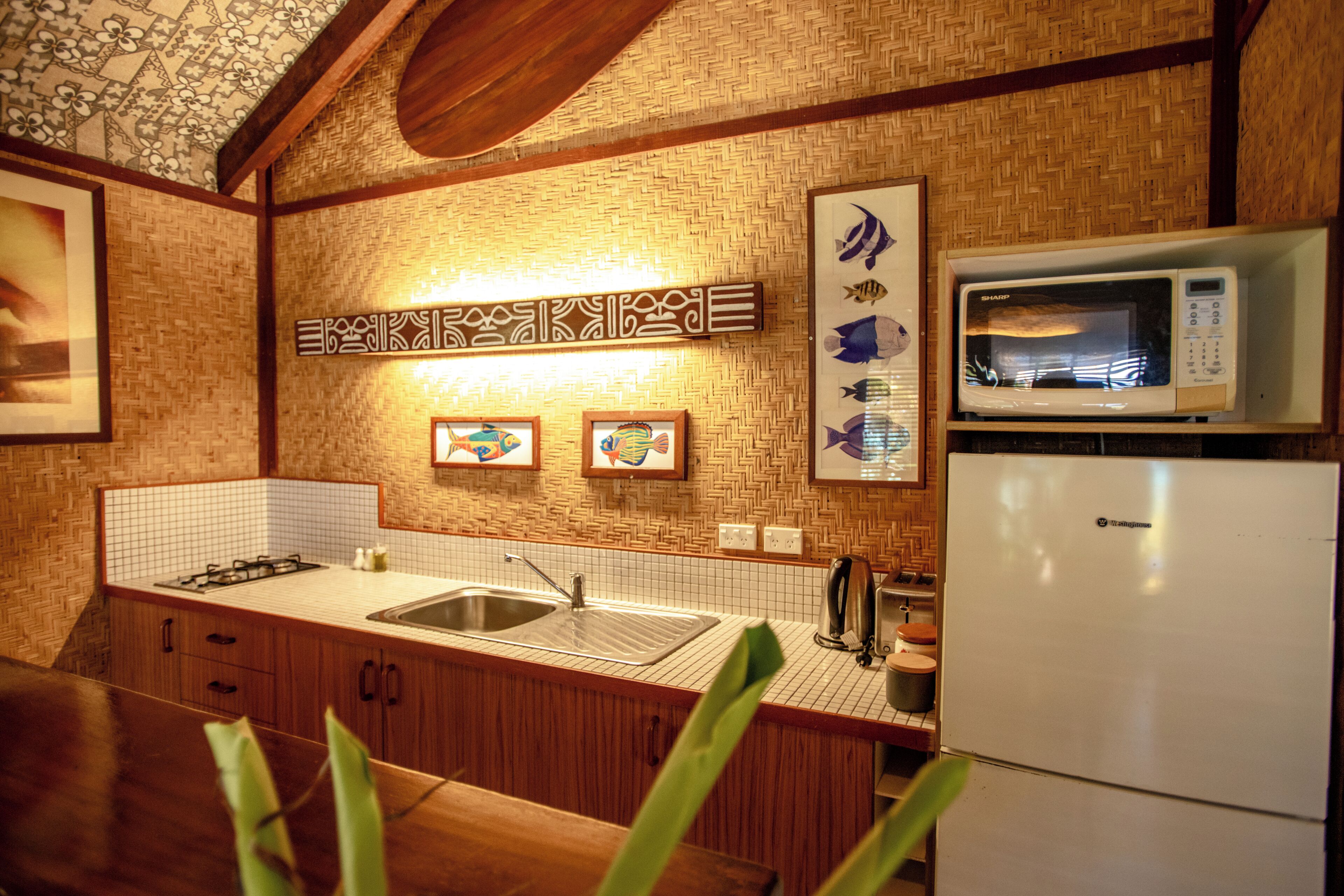 A kitchen with a microwave, sink, and wooden cabinets.