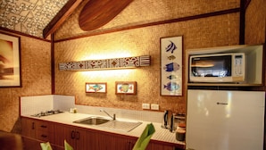 A kitchen with a microwave, sink, and wooden cabinets. - Rarotonga Beach Bungalows (Rarotonga)
