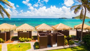 Un complexe hôtelier de bord de mer avec des bungalows aux toits de chaume, une terrasse en bois et une vue sur l’océan.