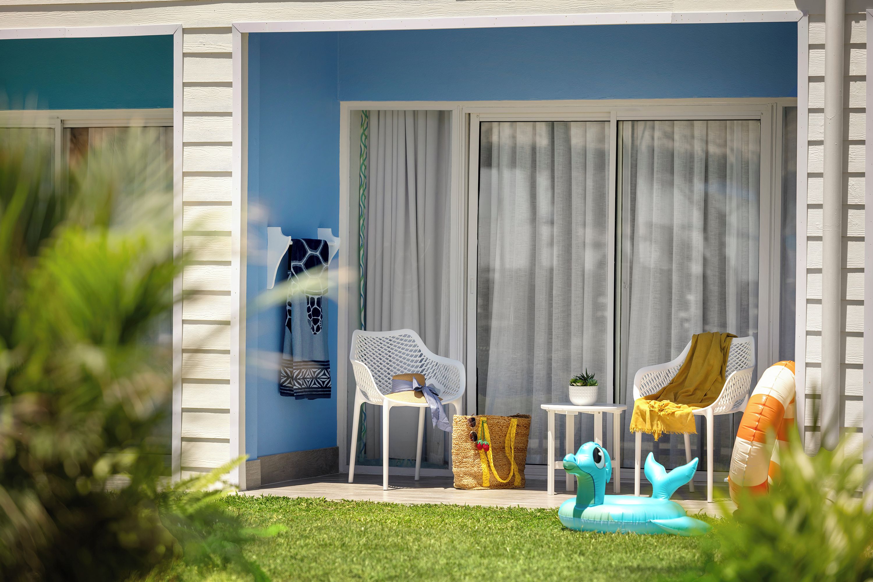 A patio with two white chairs, a small table, and a blue inflatable pool.