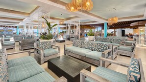 A spacious lounge area with multiple seating options, including sofas and chairs, arranged in an open layout.