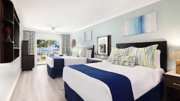 A modern hotel room with two beds, a balcony with a view, and a large painting on the wall.