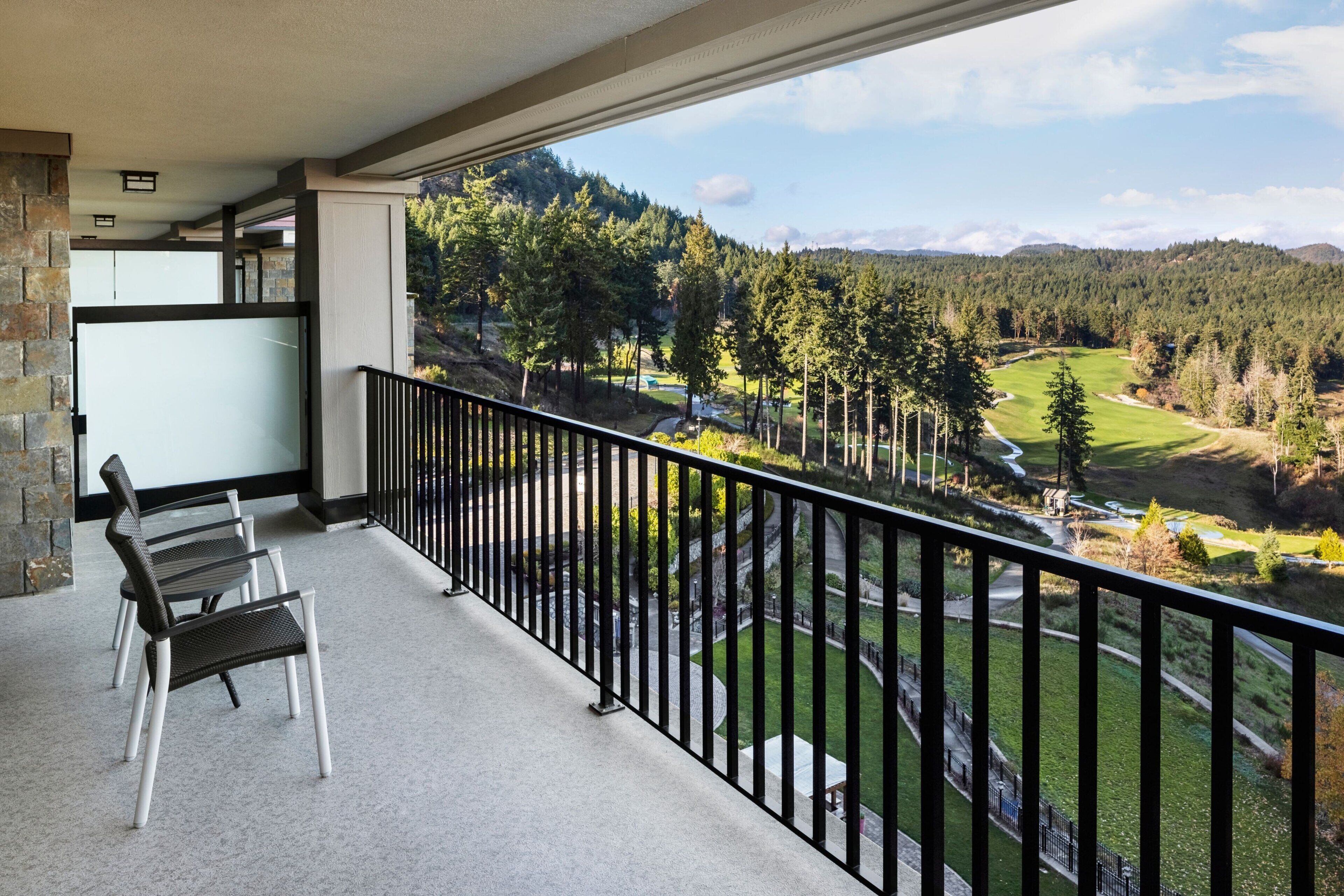 Un balcón con vistas a un campo de golf y colinas boscosas.