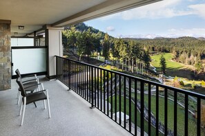Un balcón con vistas a un campo de golf y colinas boscosas.