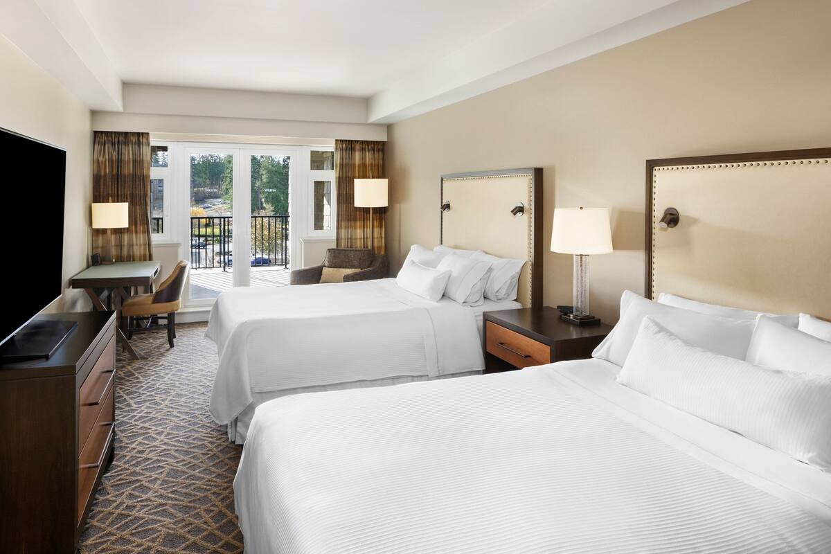 Une chambre d’hôtel avec deux lits, un bureau, une chaise et un téléviseur.