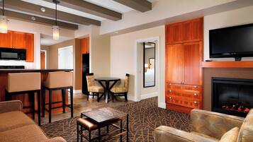 A modern living room with a fireplace, wooden cabinets, a flat-screen TV, and a dining area with chairs and a table.