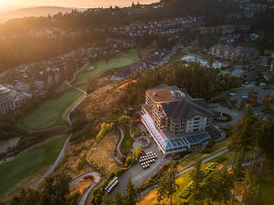 An aerial view of a resort with a large building, golf course, and surrounding residential area.