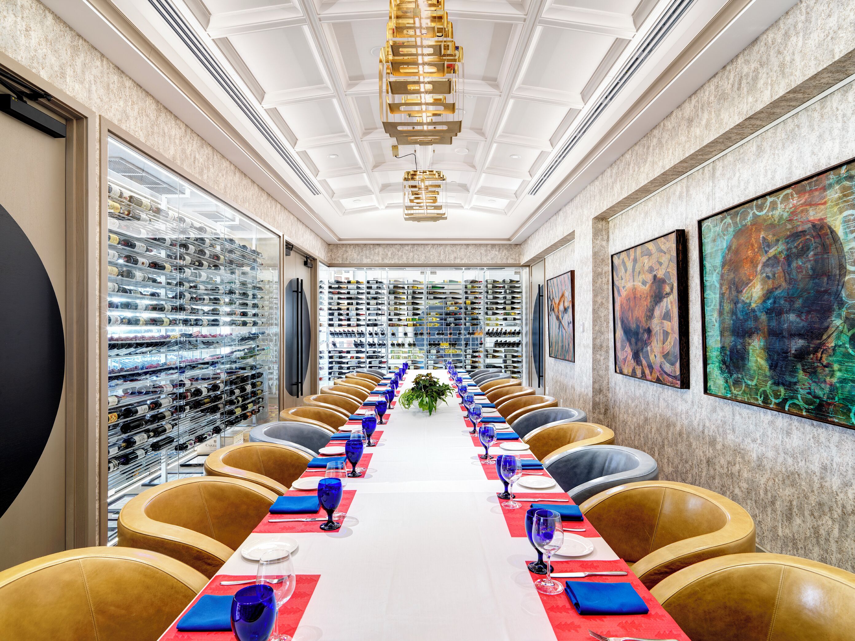 A long table with chairs, a wine rack, and artwork on the walls.