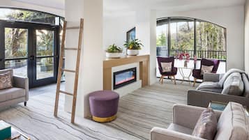 A modern living room with a fireplace, comfortable seating, and large windows offering a view of the outdoors.