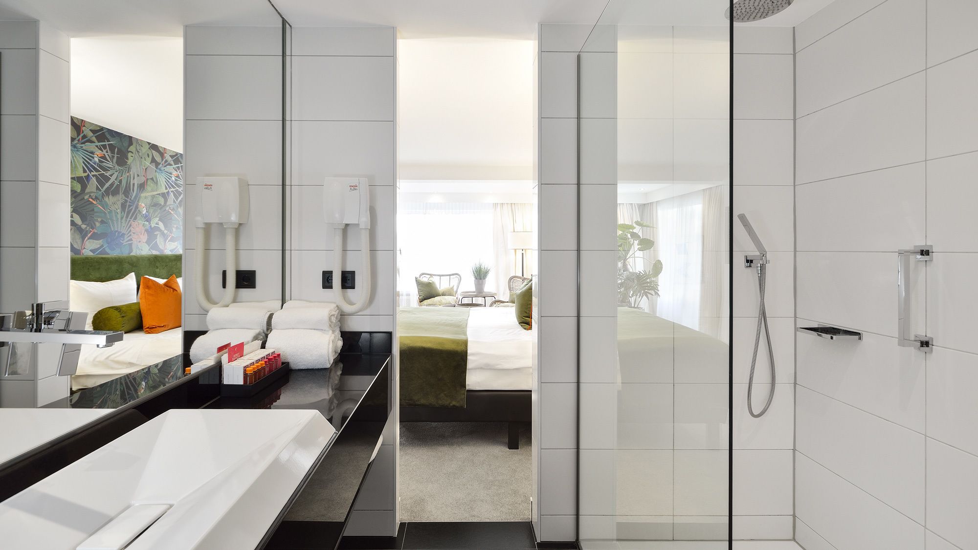 A modern hotel room with a large mirror, a bathtub, a bed with green bedding, and a shower area.