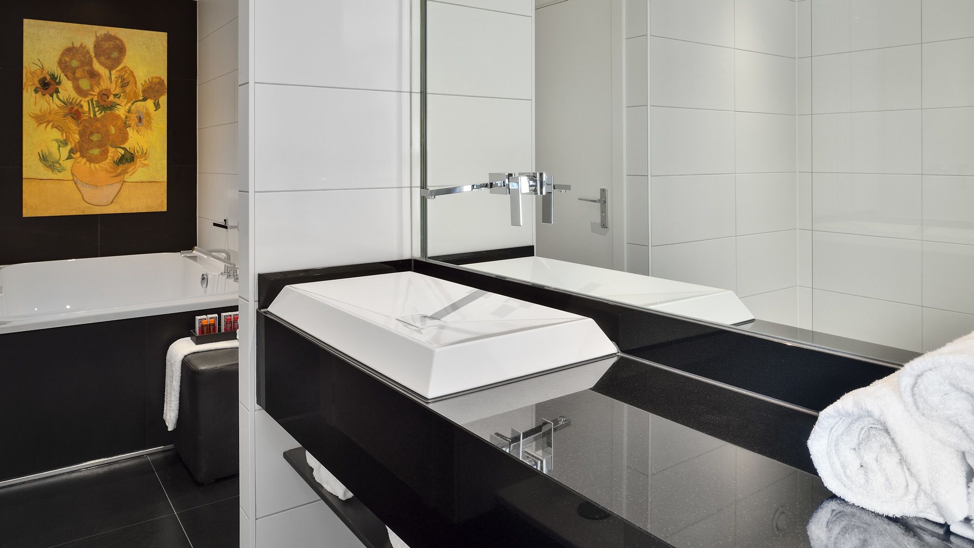 Une salle de bain moderne avec un grand miroir, deux lavabos, une baignoire et un porte-serviettes.