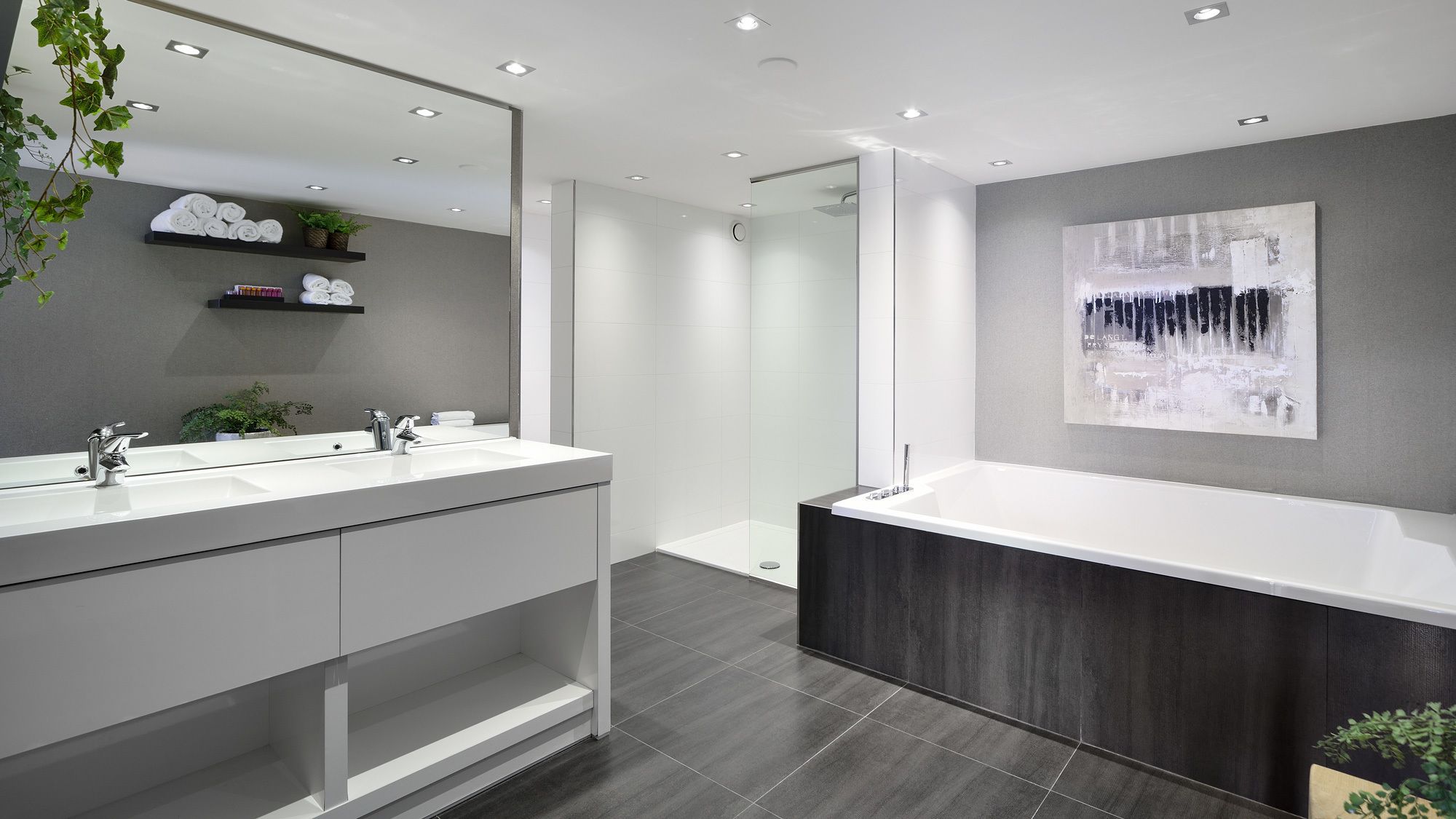 A modern bathroom with a large mirror, dual sinks, a shower, and a dark wood vanity.