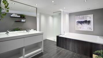 A modern bathroom with a large mirror, dual sinks, a shower, and a dark wood vanity.