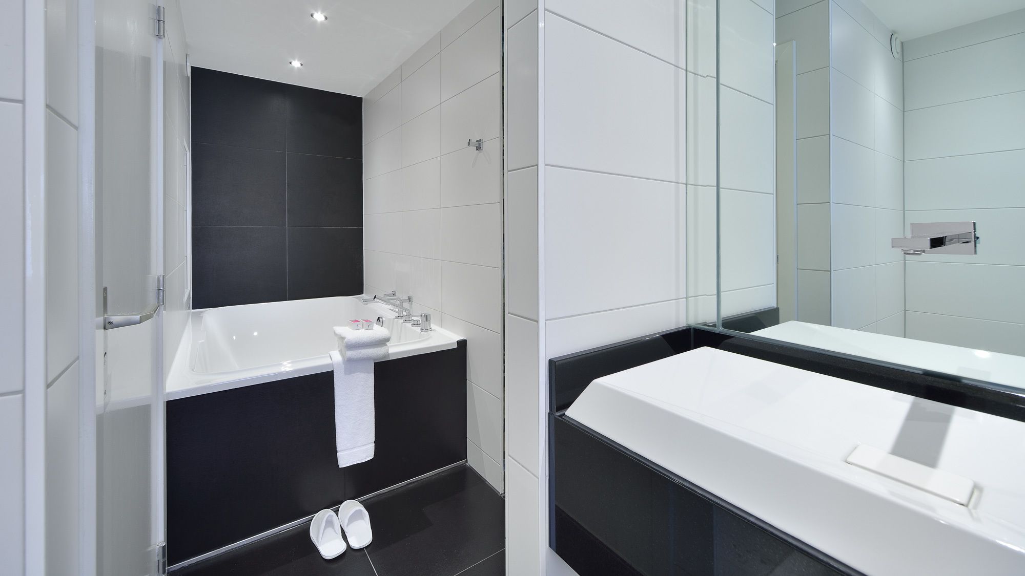 A modern bathroom with a large bathtub, a separate sink, and a glass shower enclosure.