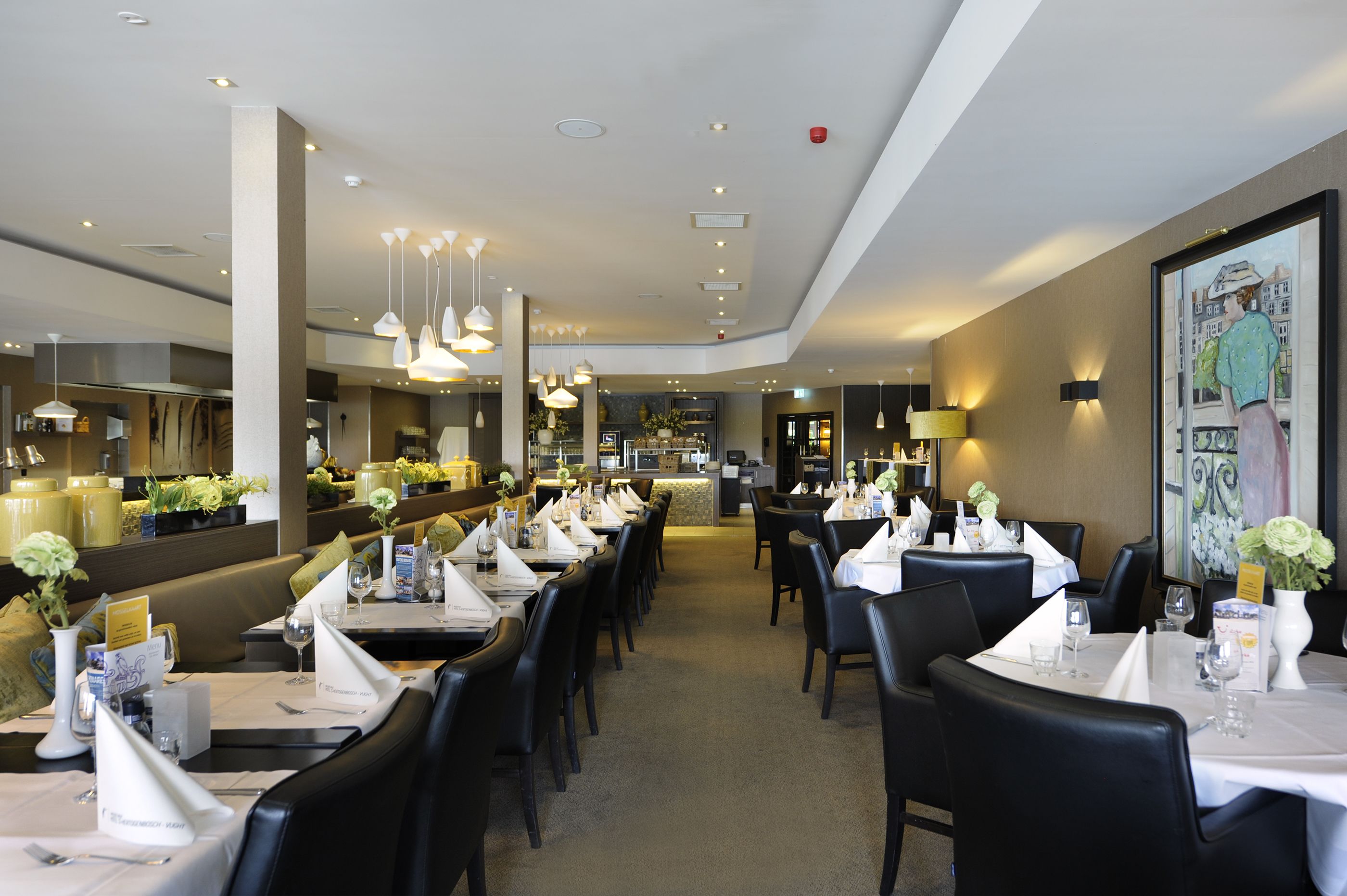 Un restaurante moderno con varias mesas, sillas negras y lámparas colgantes.