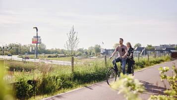 Een koppel fietst over een verhard pad, met een hotelschilt in de achtergrond.
