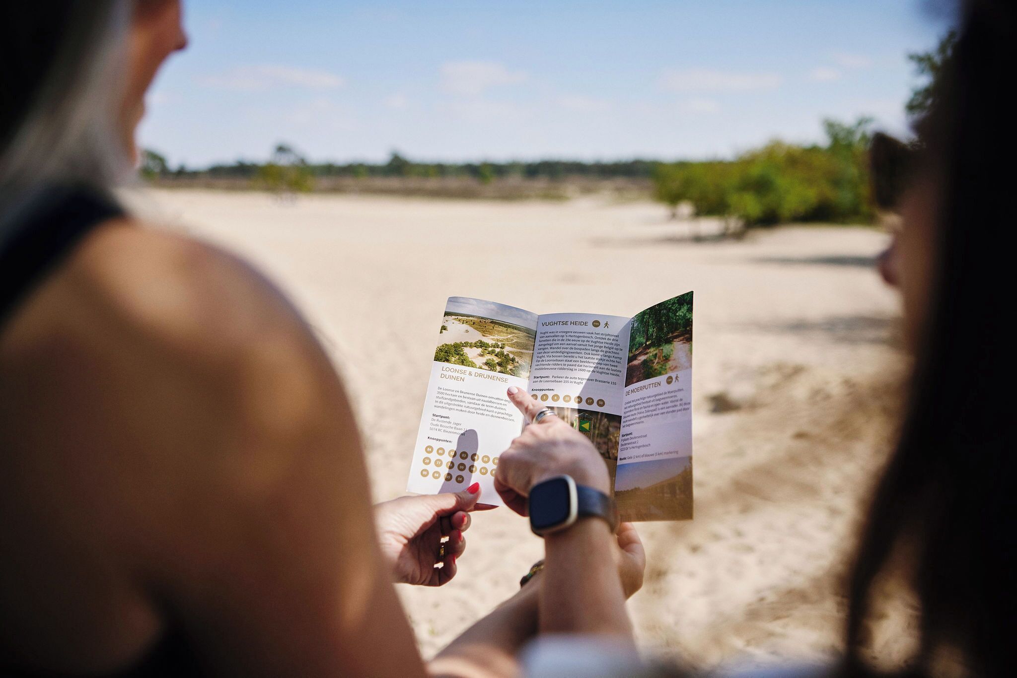 A person reading a brochure on a beach.