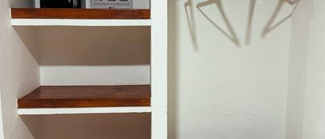 A closet with wooden shelves, a hanging rod, and a built-in bench.