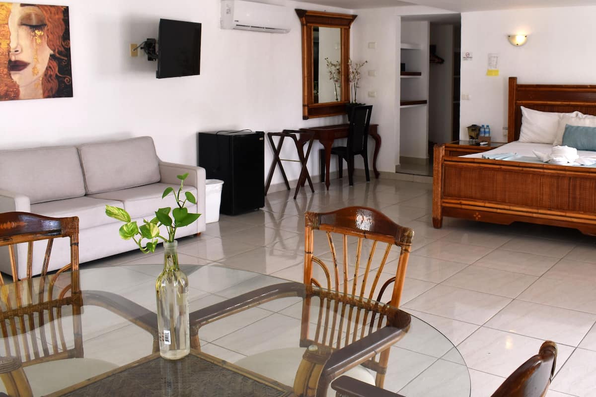 Une chambre d’hôtel comprenant un lit, un canapé, une table à manger avec des chaises et un téléviseur.