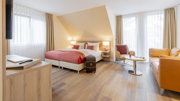 Una habitación de hotel moderna con una cama, un escritorio, un sofá y un televisor.