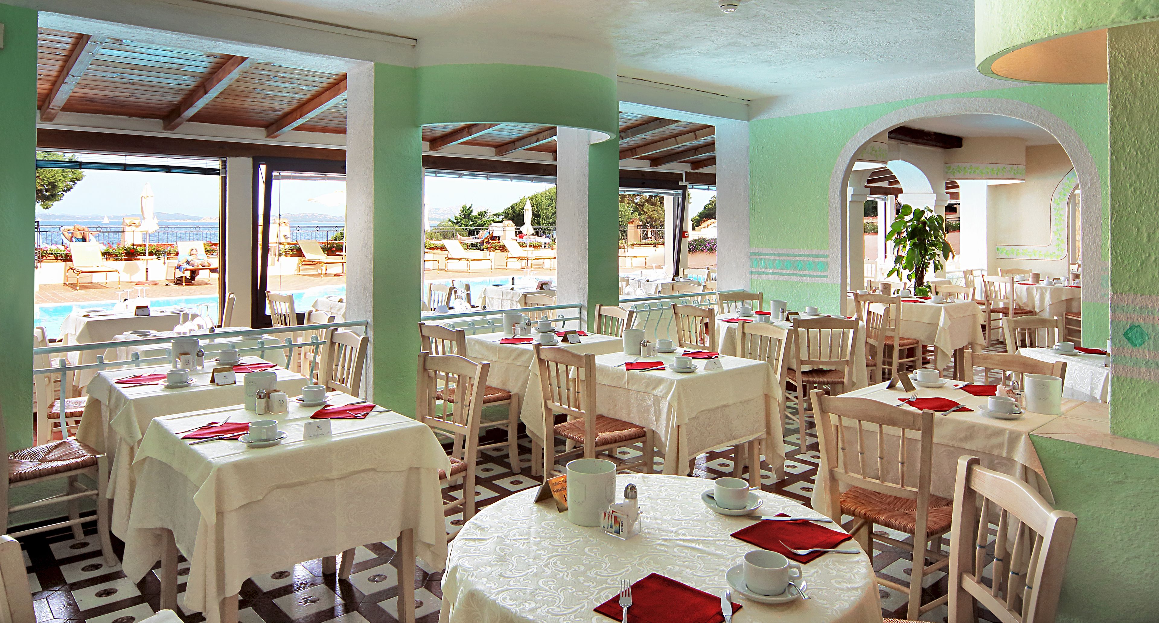 A restaurant with outdoor seating overlooking a pool and the sea.