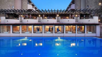 A hotel with a pool, outdoor seating, and stone architecture.