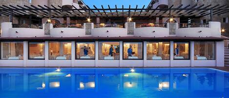 Un hotel con piscina, mobiliario exterior y arquitectura de piedra.