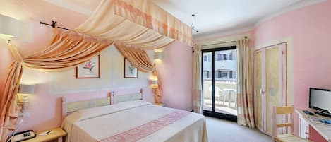 A hotel room with a bed, bedside table, lamp, and a desk with a chair.