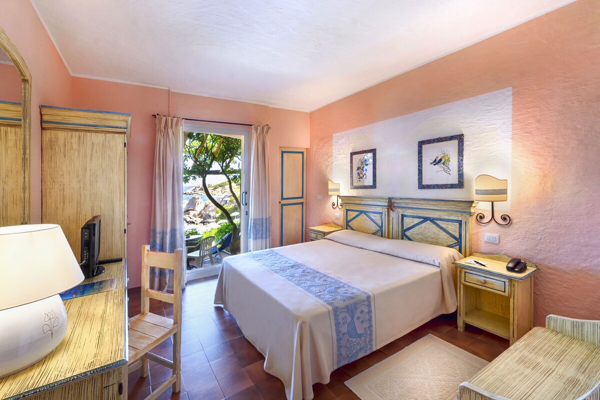 A bedroom with a bed, bedside tables, a chair, a desk, and a window with curtains.