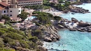 Ett hotell vid kusten med pool, strand och en klippig terräng.