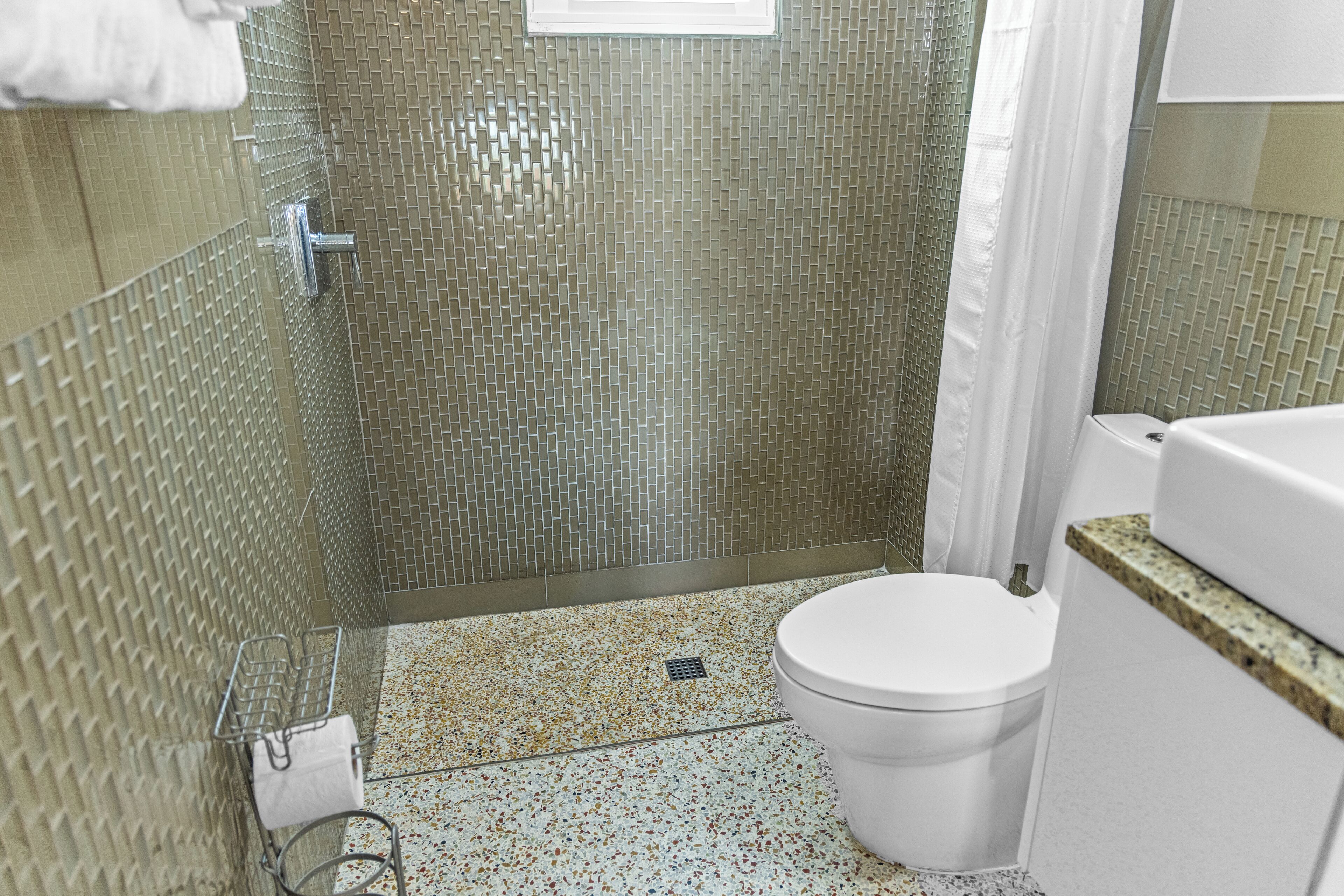A bathroom with a shower, toilet, and a sink.