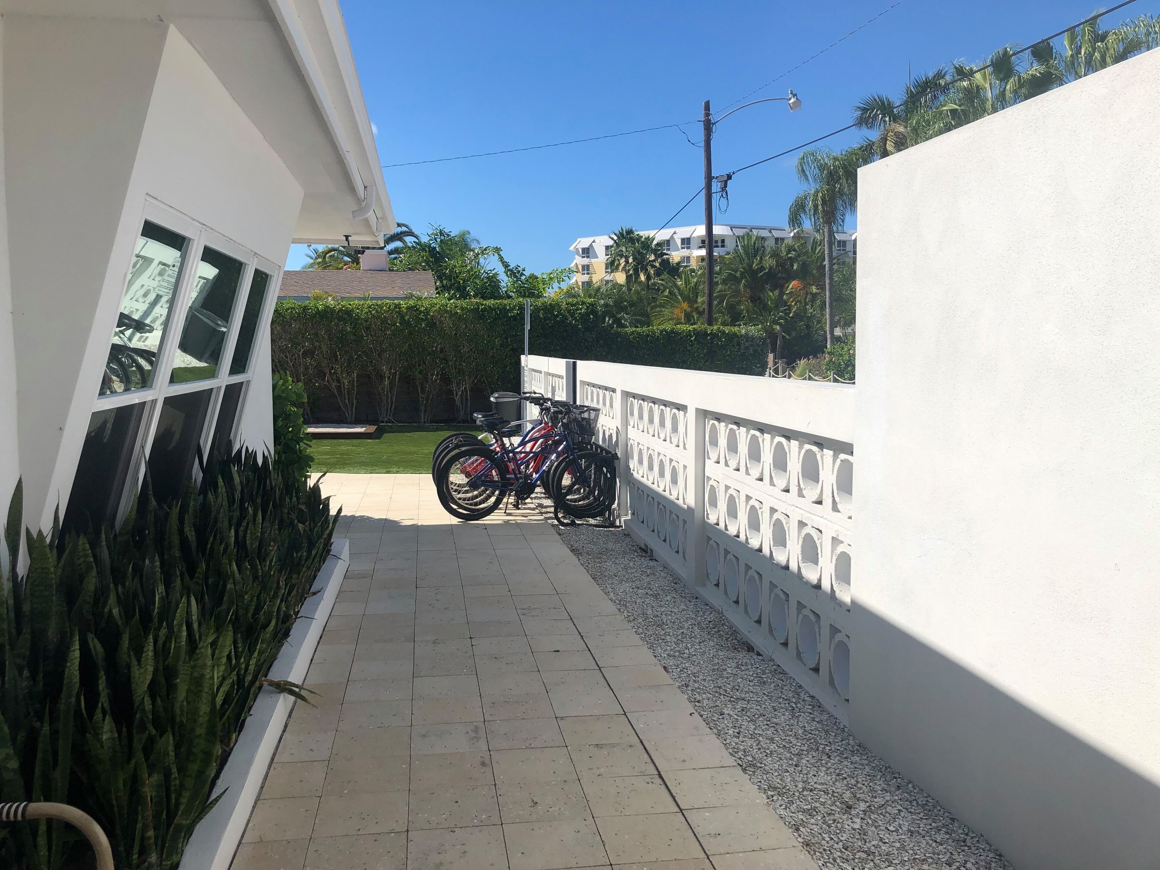 A narrow paved pathway leading to a building with a white exterior and a window.