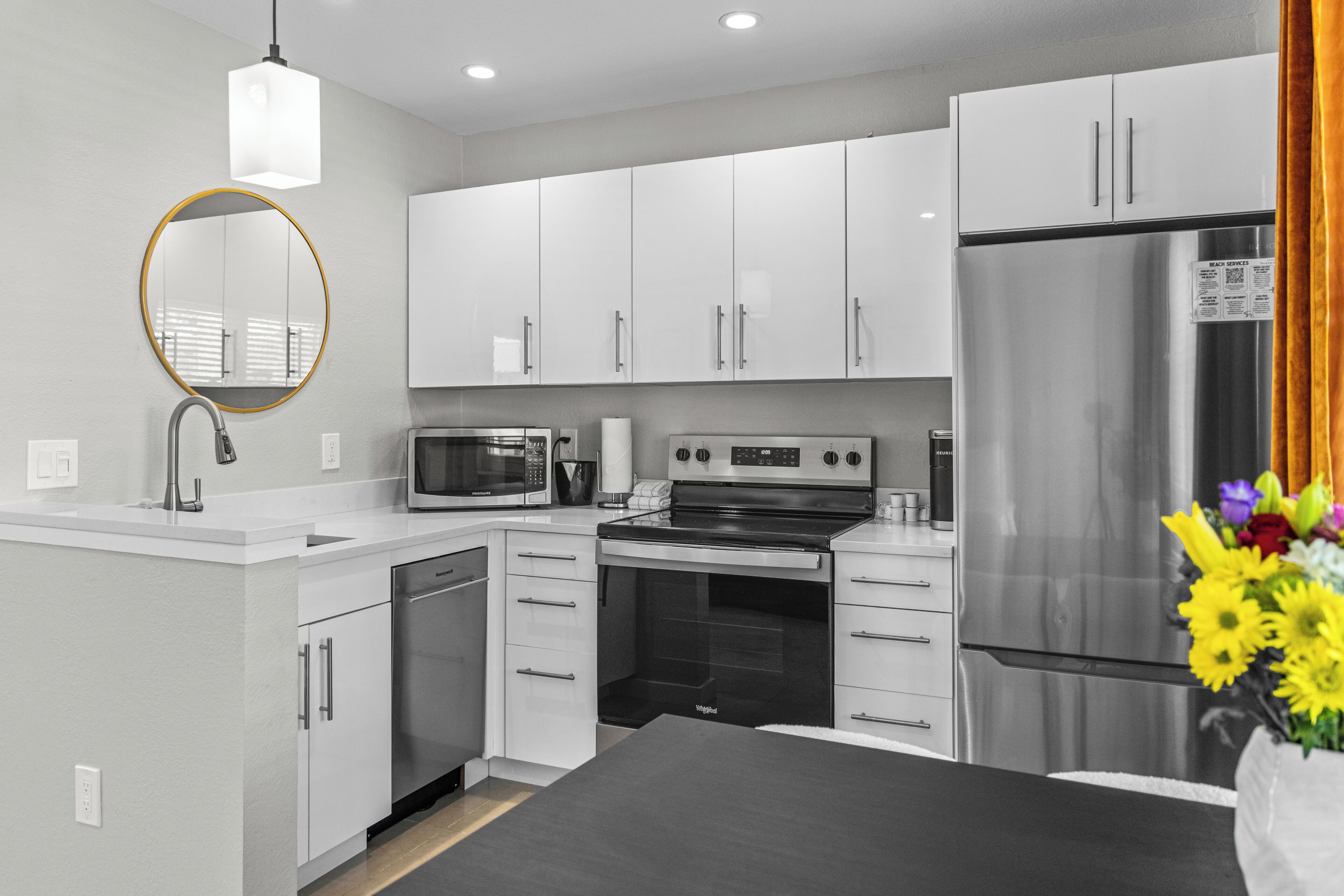 A modern kitchen with white cabinets, a stainless steel refrigerator, a microwave, and a stove.