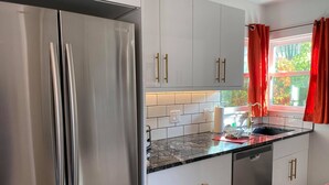 Una cocina moderna con armarios blancos, electrodomésticos de acero inoxidable y encimera de mármol.