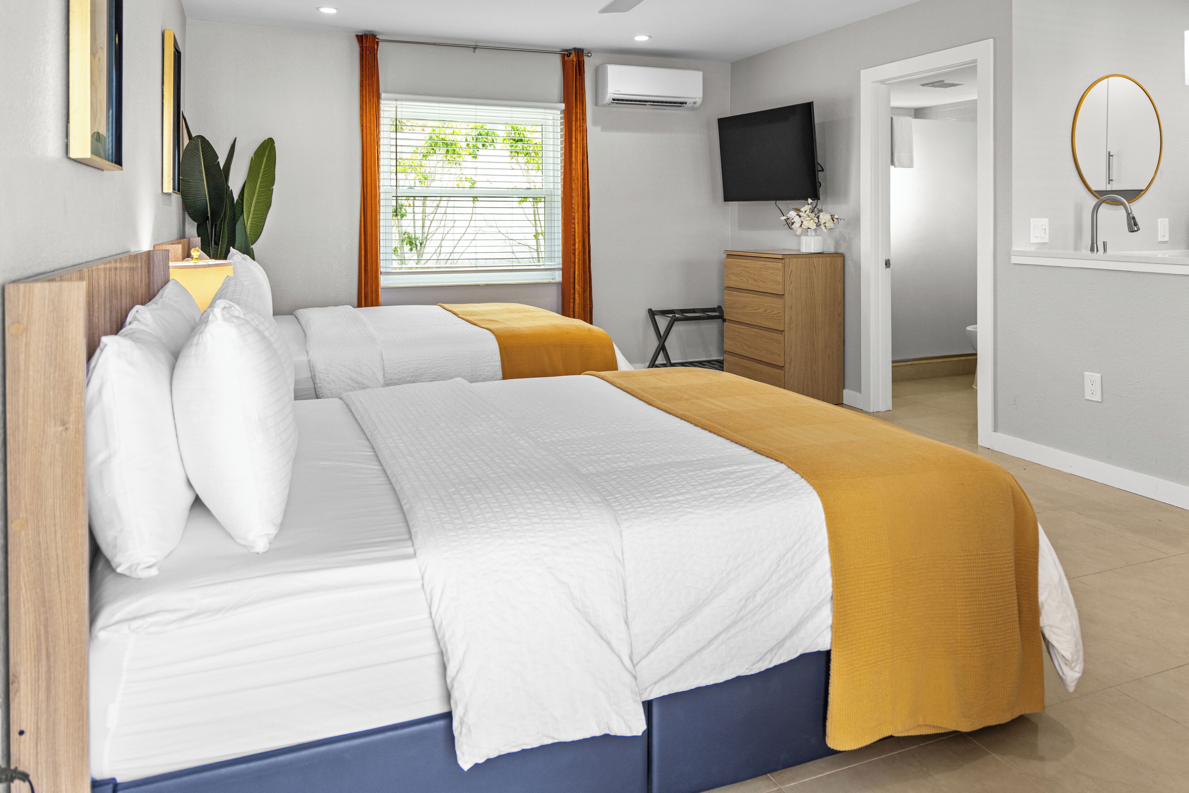 Een hotelkamer met een bed, een televisie, een badkamer en een raam met gordijnen.
